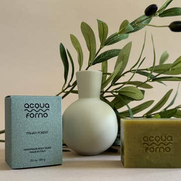 Acqua Forno soap and packaging with a vase and greenery on a neutral background